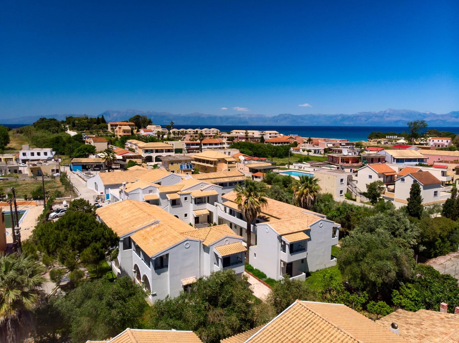 Un área residencial costera con casas de techo de tejas y una vista despejada del mar.