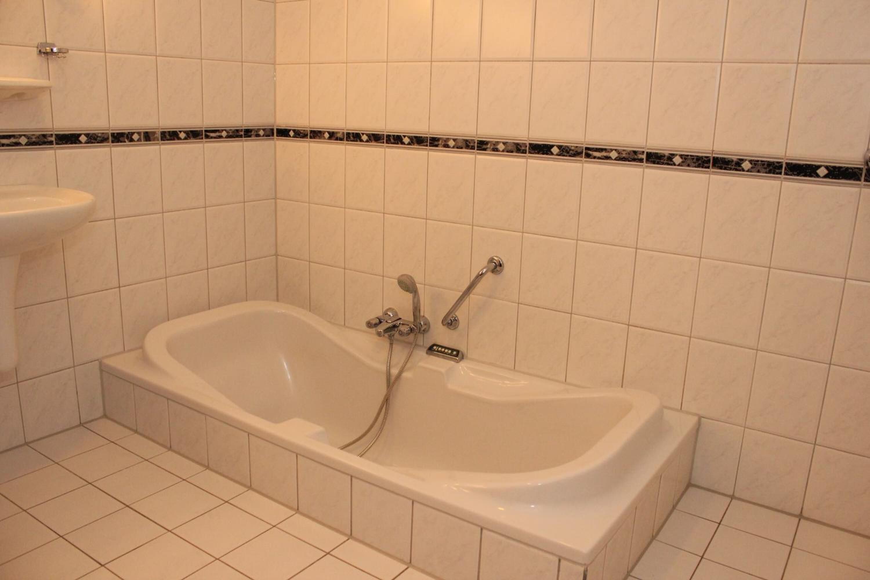 Ein Badezimmer mit Badewanne, Waschbecken und Fliesen.