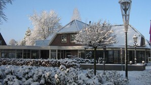 Ein Gebäude mit schneebedecktem Dach, Glasfassade und einem Schild mit der Aufschrift 'Hotel Restaurant Pizza'.