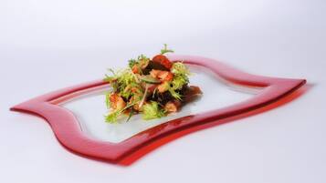 A dish with seafood and greens on a white plate with a red rim.