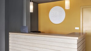 Una recepción con un letrero circular que dice "B&B HOTELS" y un portátil encima.