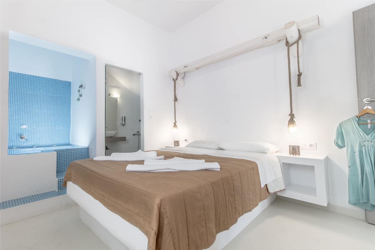 A modern hotel room with a large bed, a built-in shower, and a hanging towel rack.