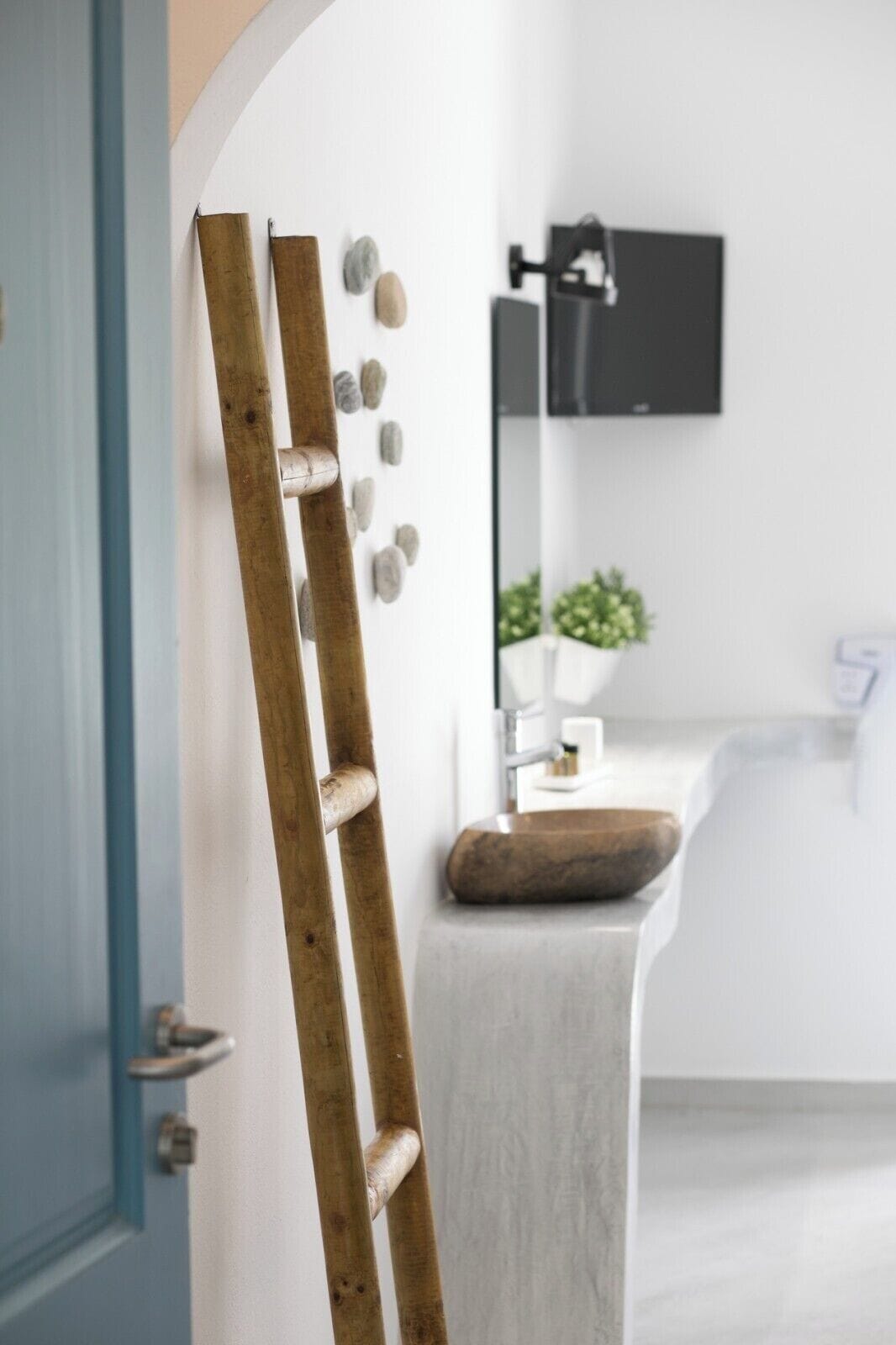 Ein Badezimmer mit einer Holzleiter, die an der Wand lehnt, einem Waschbecken und einem Spiegel.