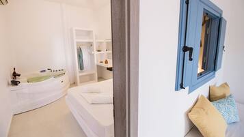 A bedroom with a bed, a window with blue shutters, and a white wall.