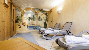 Een spa-ruimte met houten wanden, een muurschildering en twee massagestoelen met handdoeken.