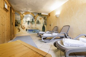 Un cuarto de spa con paredes de madera, un mural y dos sillones de masaje con toallas.