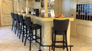 Een bar met een toonbank, barstoelen en een betegelde vloer.