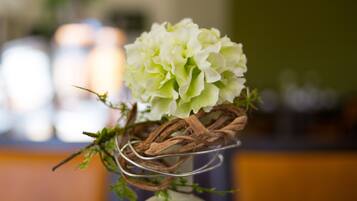 A white vase with a green plant and a white flower arrangement.