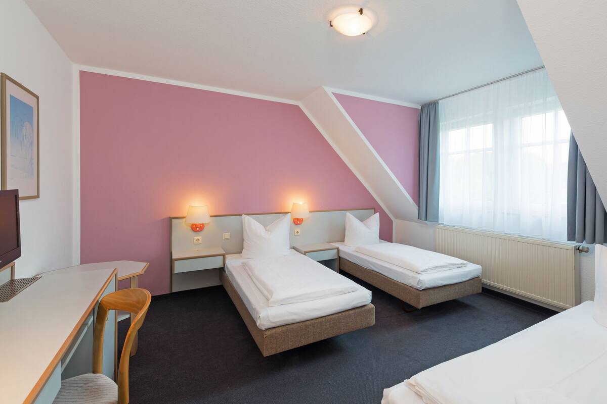 A hotel room with two beds, a desk, and a chair.