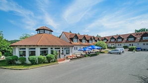 A row of traditional-style buildings with a central gazebo, outdoor seating, and a clear sky. - Motel Hormersdorf (Schnaittach)