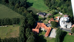 Vista aérea de una propiedad rural con una edificación principal, varias construcciones más pequeñas y vegetación circundante.