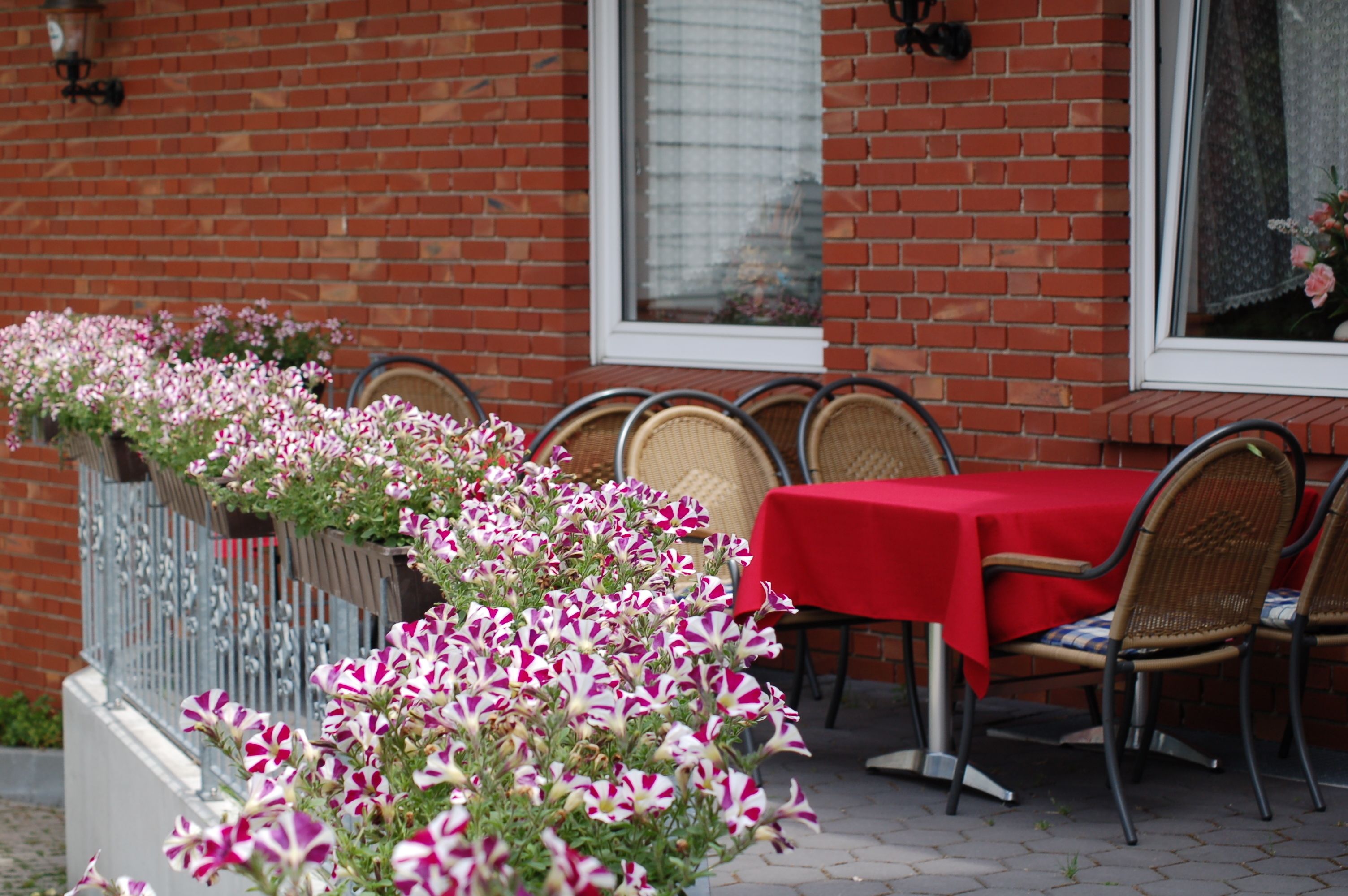 A brick building with a red table and chairs set outside.