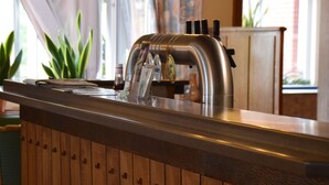 Una zona de bar con mostrador de acero inoxidable, paneles de madera y grifo de cerveza.