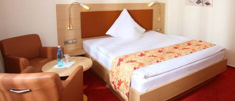 A hotel room with a bed, a desk, a chair, and a nightstand.