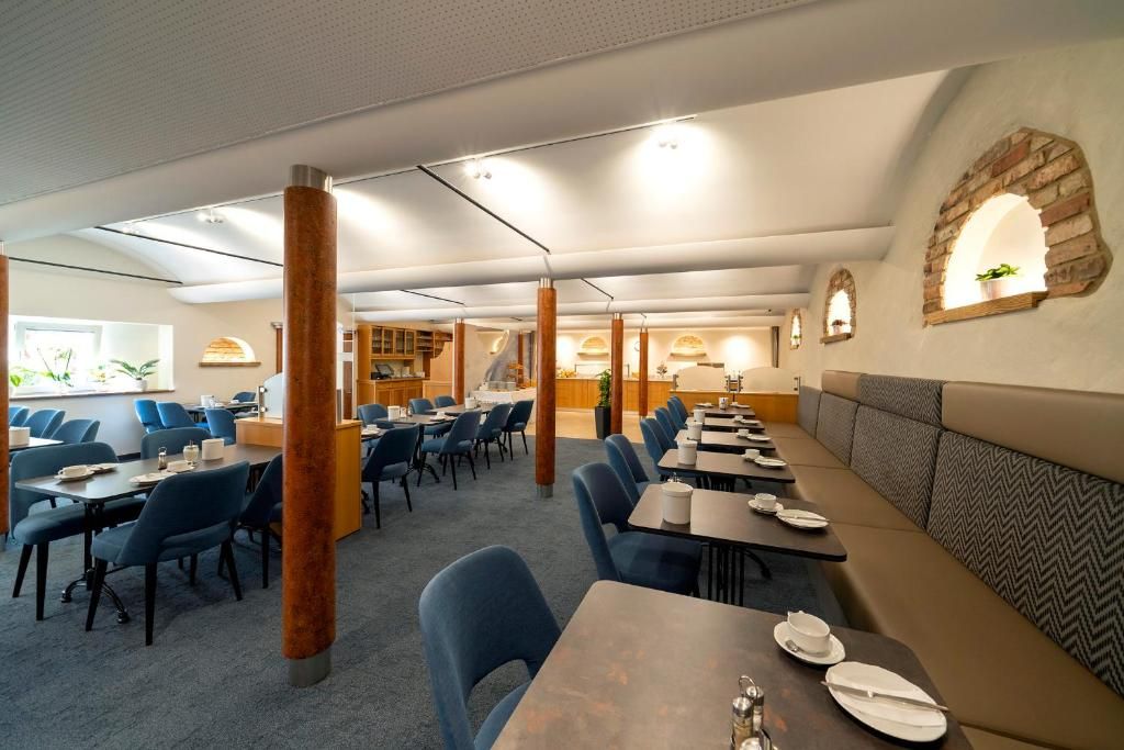A restaurant with multiple dining tables and booths, a bar area, and a seating arrangement with blue chairs and cushioned booths.