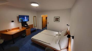 A hotel room with a bed, a desk, a television, and a small bathroom.