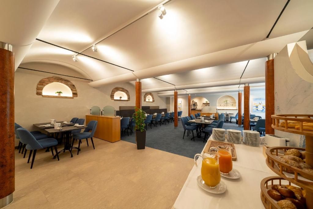 Ein Essbereich eines Hotels mit Tischen, Stühlen und Frühstücksangeboten.