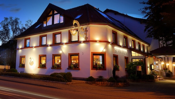 Un hotel de estilo arquitectónico europeo tradicional, con una entrada destacada, múltiples ventanas y una fachada bien iluminada.