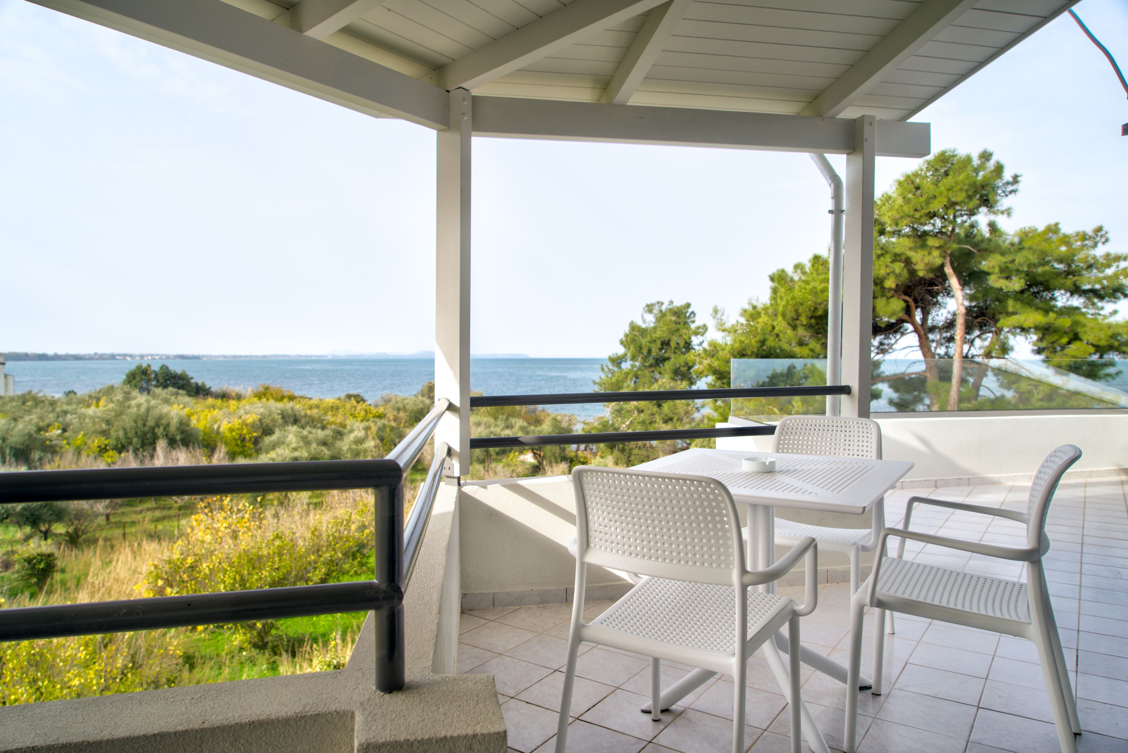Un espacio al aire libre cubierto con una mesa y sillas, con vistas a un paisaje costero.