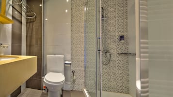 Un baño moderno con inodoro, cabina de ducha y lavamanos.