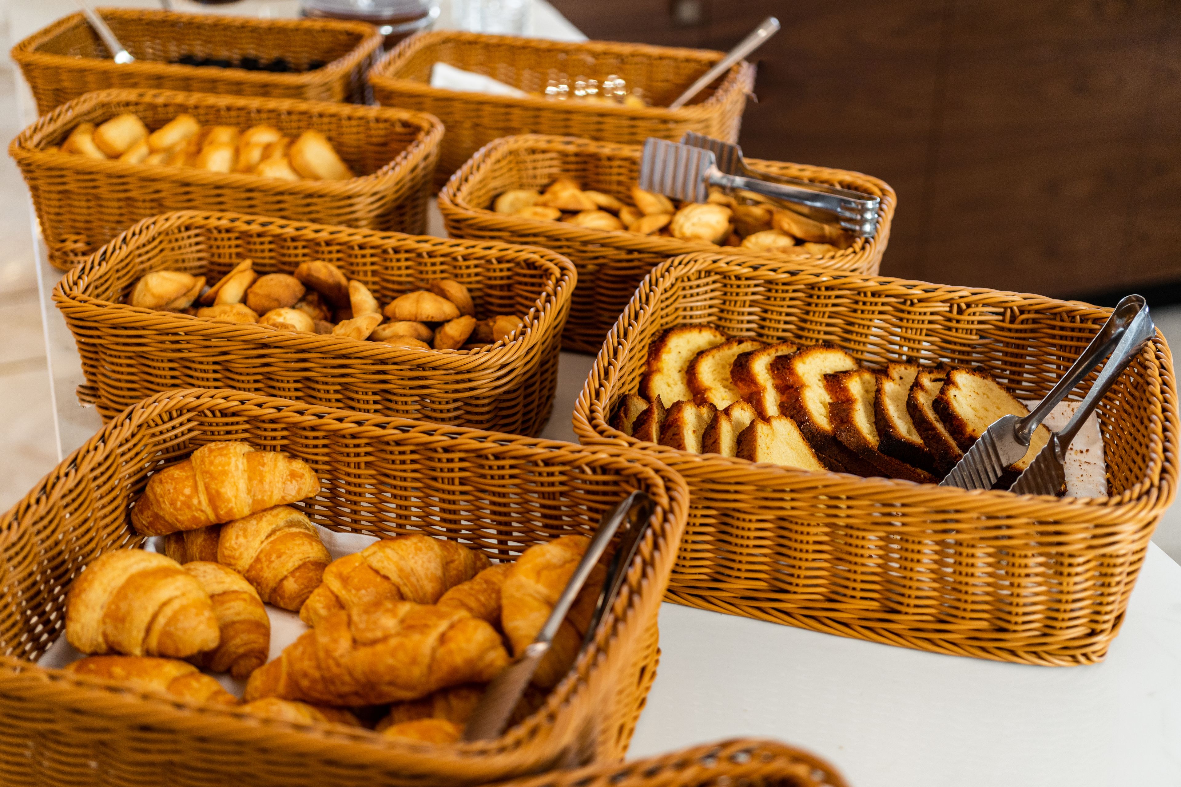 Cestos de vime repletos de pães e croissants variados.