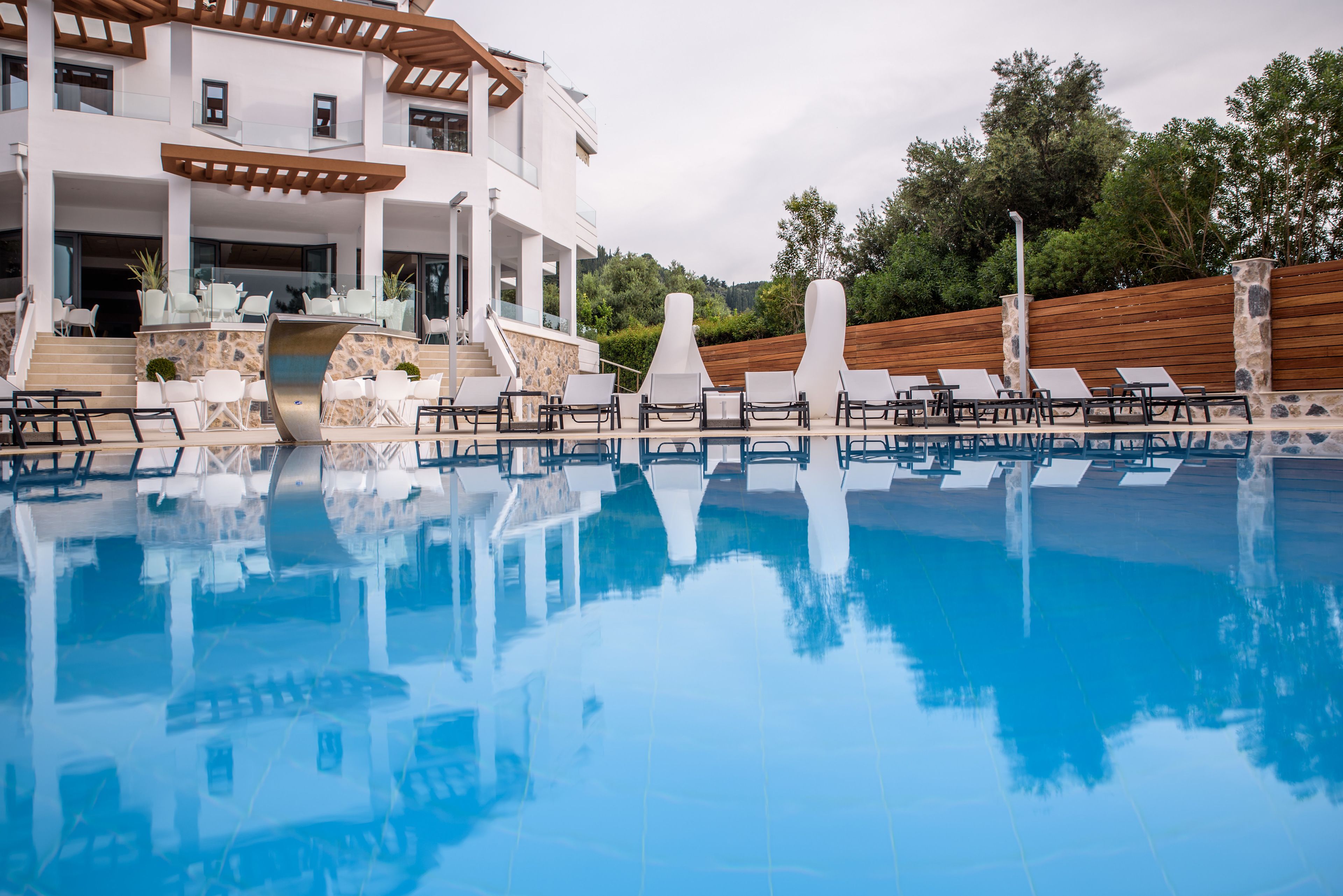 Una piscina con sillas de descanso y un edificio de fachada de piedra y terraza de madera.