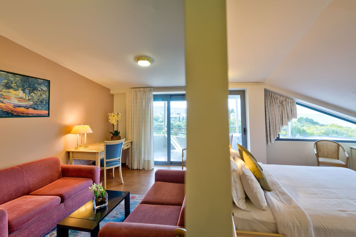 A hotel room with a bed, a sofa, a desk, and a chair.