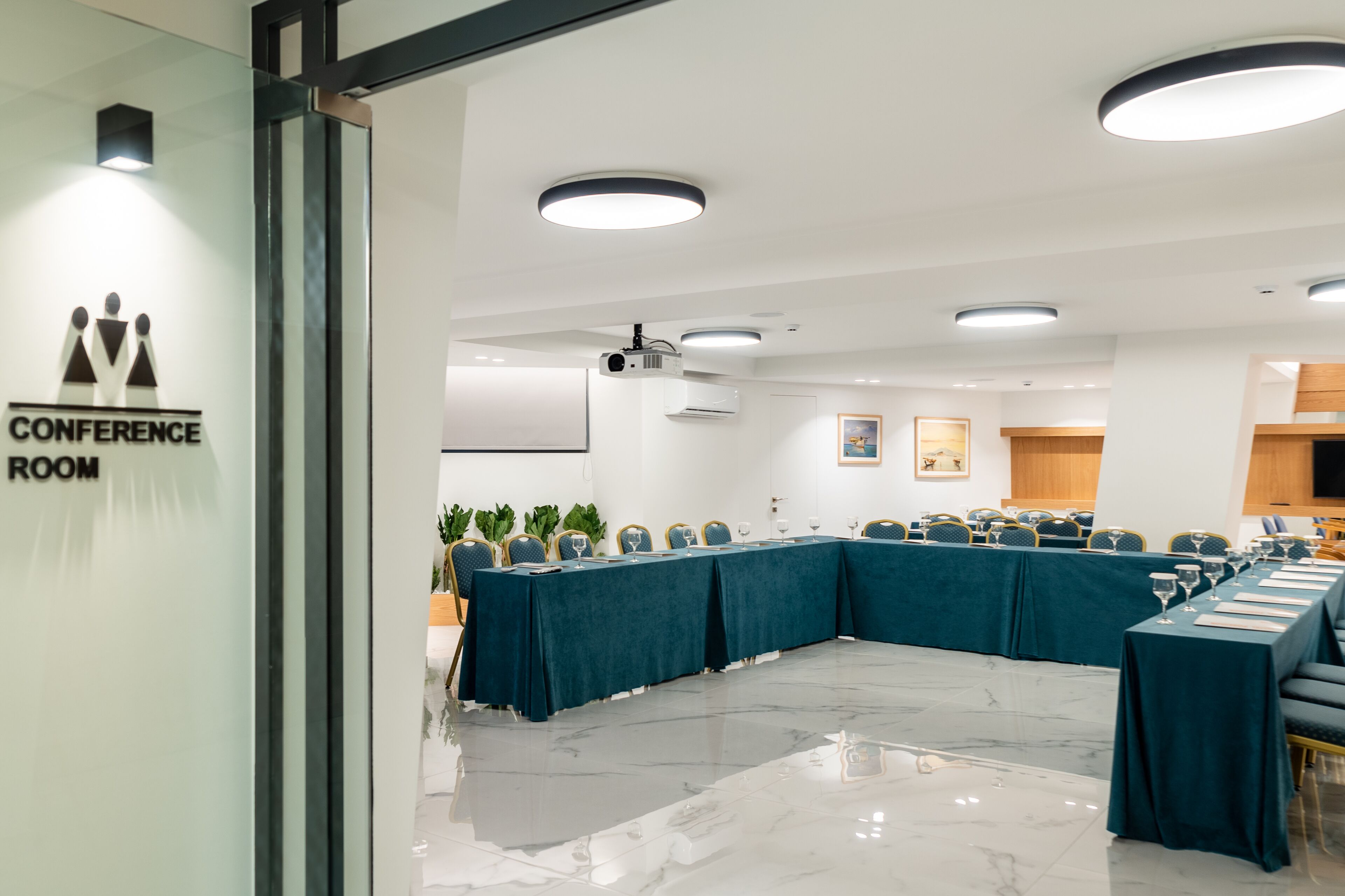 A conference room with a long table, chairs, and a glass partition.