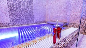A room with a patterned wall, a bed with a red bow, and a glass of water on the side. - Hotel Marie Luisa (Prague)