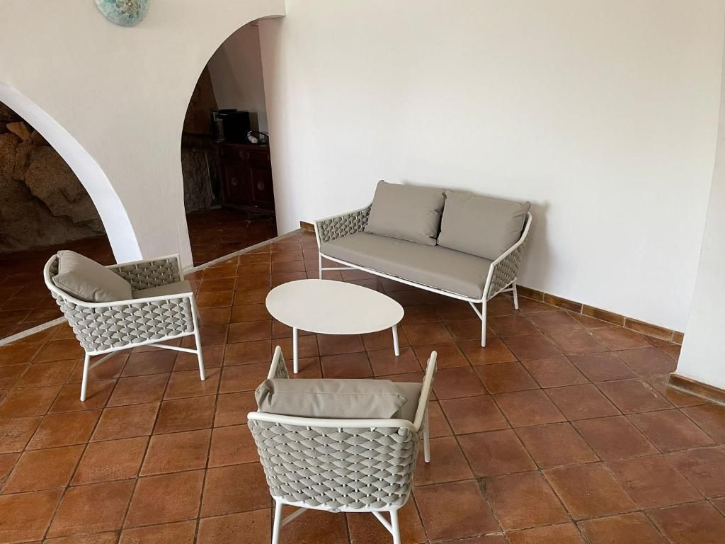 A patio area with a sofa, two armchairs, and a small round table.