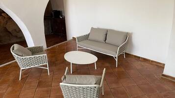 A patio area with a sofa, two armchairs, and a small round table.