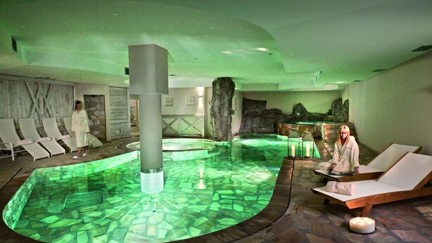A spa area with a central pool, lounge chairs, and a large pillar. - Grand Hotel Paradiso (Ponte di Legno)