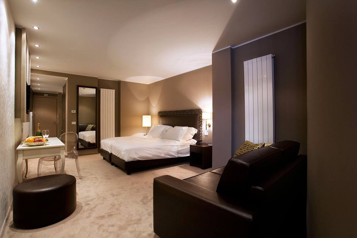 Une chambre d’hôtel avec un lit, un bureau et une chaise, un canapé et une petite table avec des fruits.