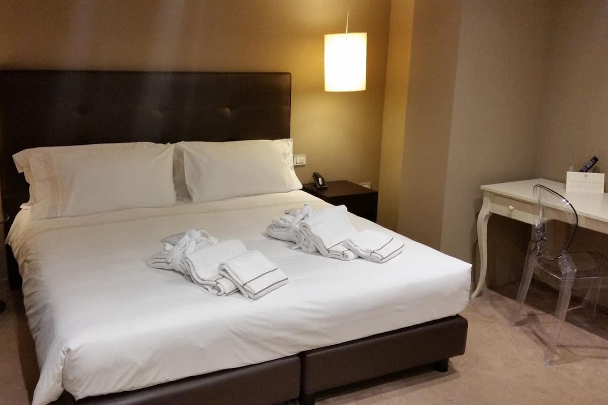 Une chambre d’hôtel avec un grand lit, deux tables de chevet, un bureau et une chaise.