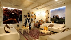 A modern living room with a fireplace, a large poster, and a view of a vineyard. - Grand Hotel Paradiso (Ponte di Legno)
