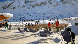 A snow-covered mountain with a ski resort in the background, featuring outdoor seating and ski equipment. - Grand Hotel Paradiso (Ponte di Legno)