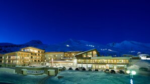 A large, multi-story hotel with a sign reading "Grand Hotel Paradiso" in a snowy mountainous area at night. - Grand Hotel Paradiso (Ponte di Legno)