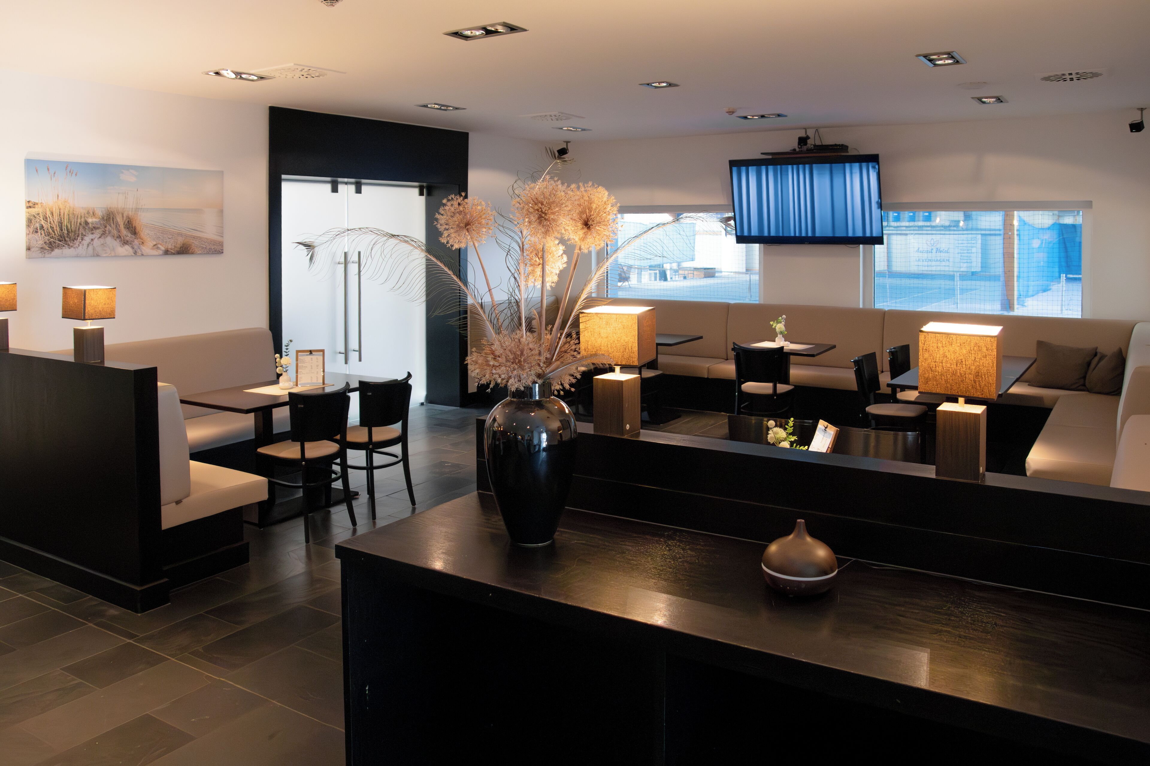 A modern hotel lobby with a reception desk, seating area, and large windows.