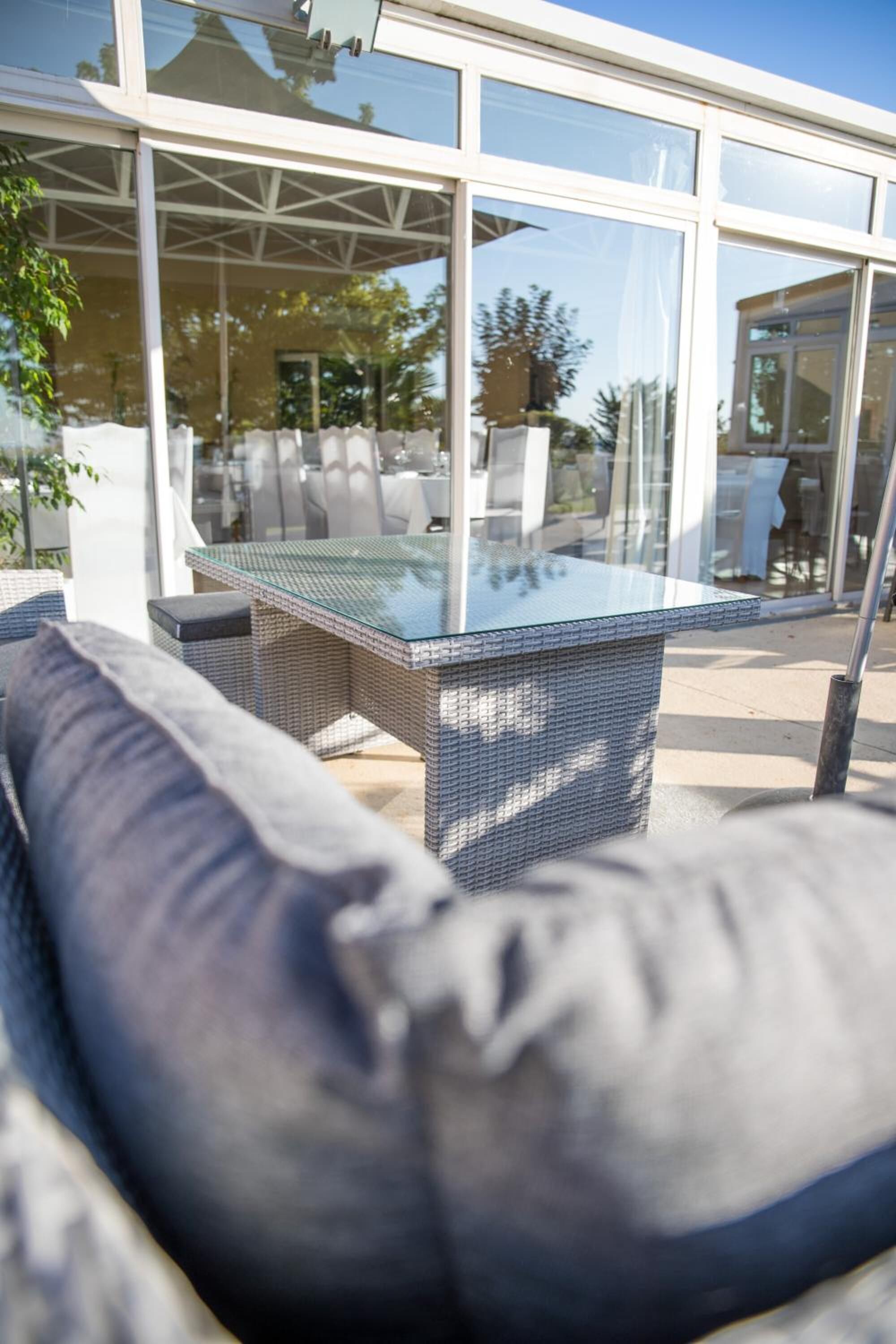 Un área de estar al aire libre con una mesa de vidrio y muebles de mimbre.