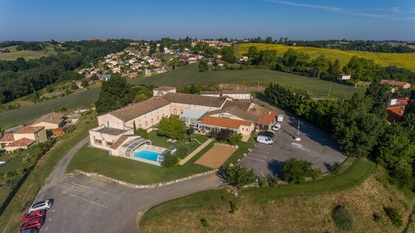 An aerial view of a large estate with multiple buildings, a swimming pool, and a parking area. - Auberge du Pastel (Nailloux)