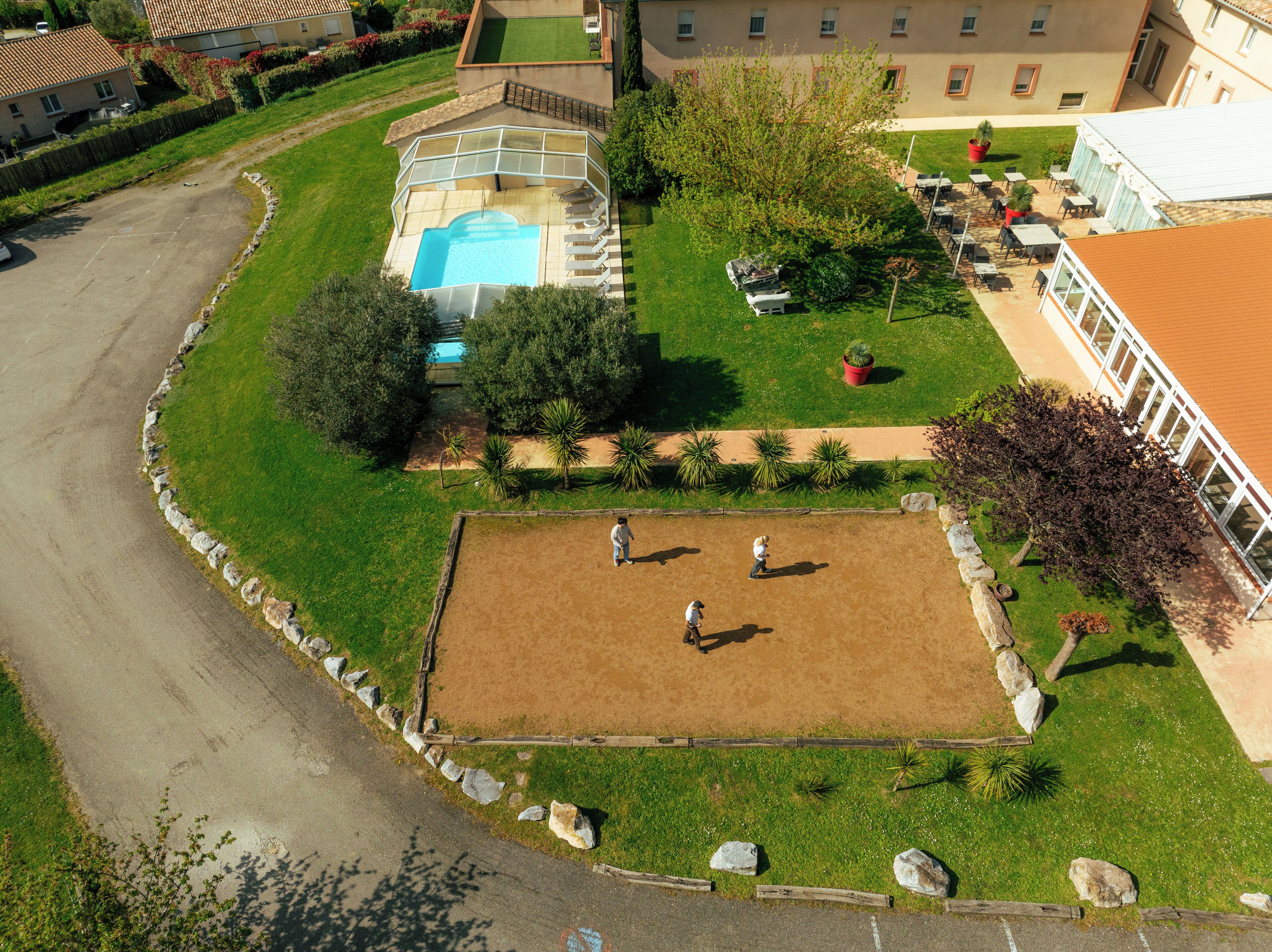 Vue aérienne d’une propriété dotée d’une piscine, d’un court de tennis et d’un patio couvert.