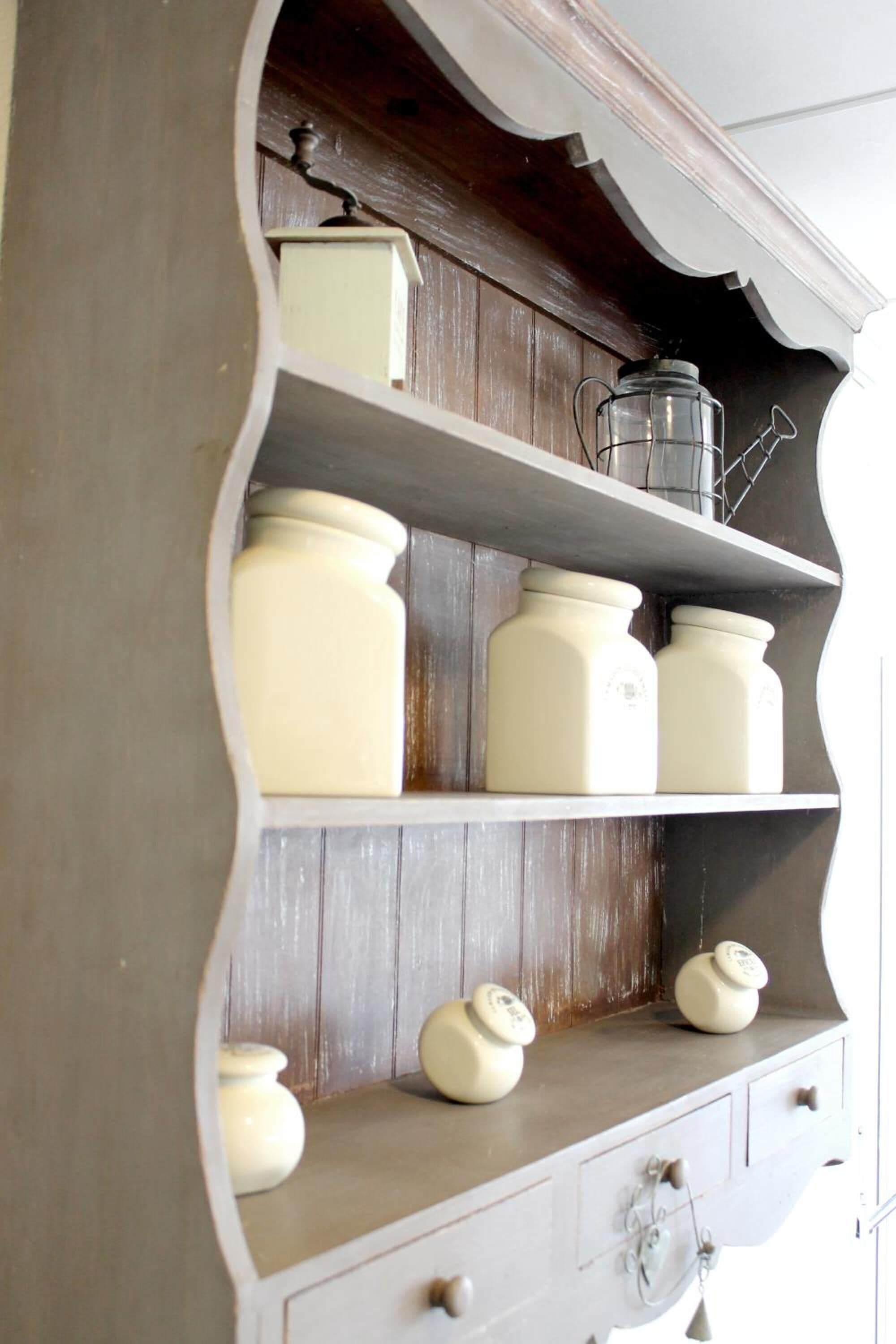 A kitchen cabinet with multiple shelves and drawers, containing various kitchen items.