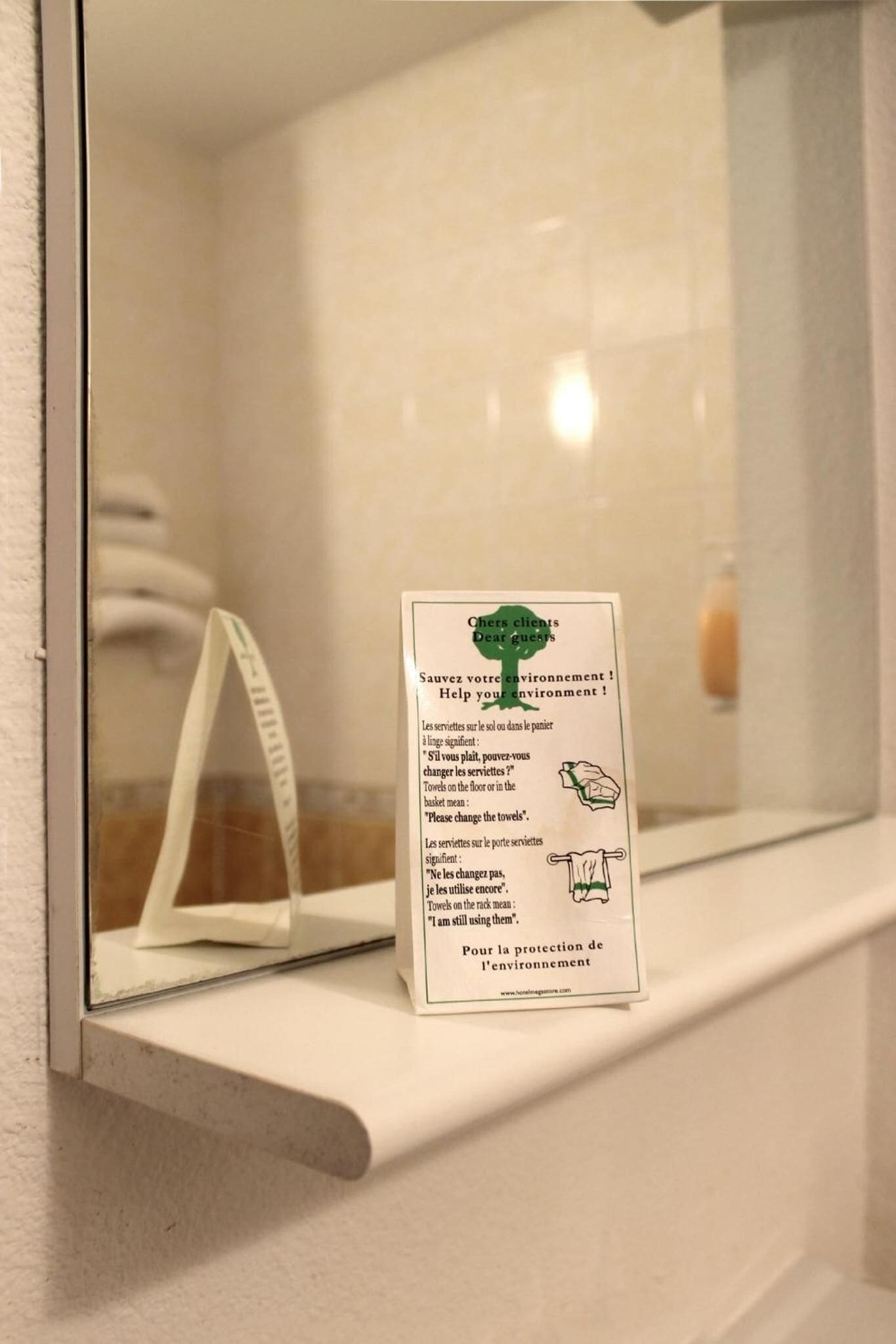Un baño con un cartel que invita a reutilizar las toallas para proteger el medio ambiente.