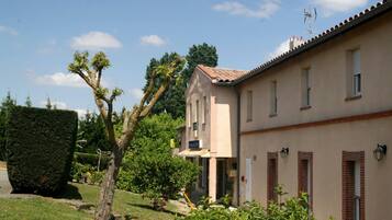 Un bâtiment à deux étages, doté d’une façade beige, de nombreuses fenêtres et d’une porte bien visible.