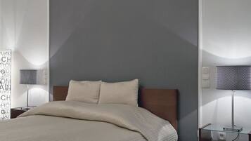 Een moderne slaapkamer met een groot bed, een nachtkastje, een lamp en een wandplank.
