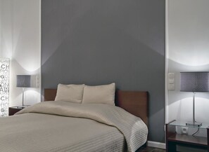 Un dormitorio moderno con una cama grande, una mesita de noche, una lámpara y un estante en la pared.