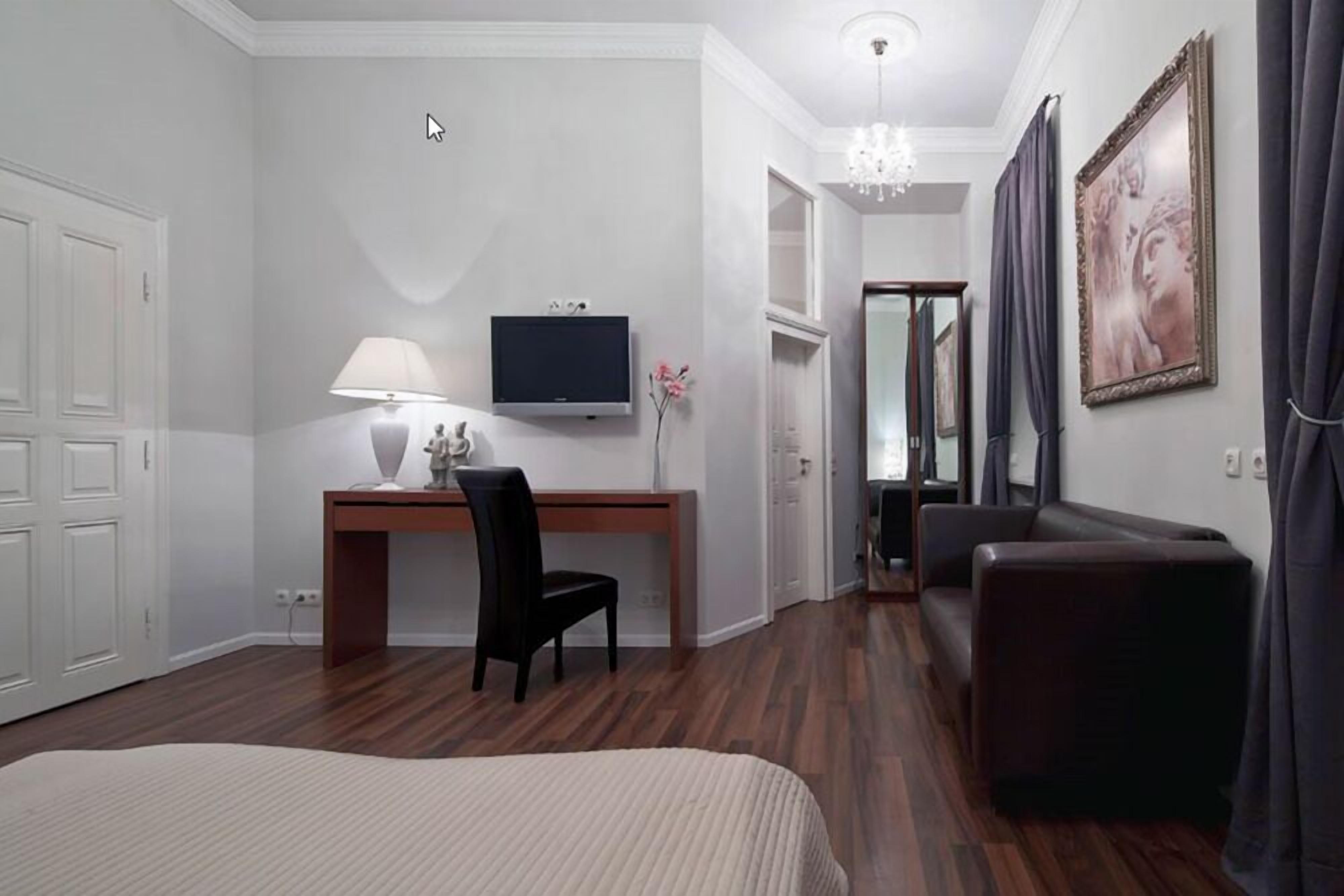 Une chambre d’hôtel comprenant un lit, un bureau avec une chaise, une télévision, un miroir et un canapé.