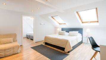 Une chambre moderne avec un lit, un canapé, un bureau et des fenêtres de toit.
