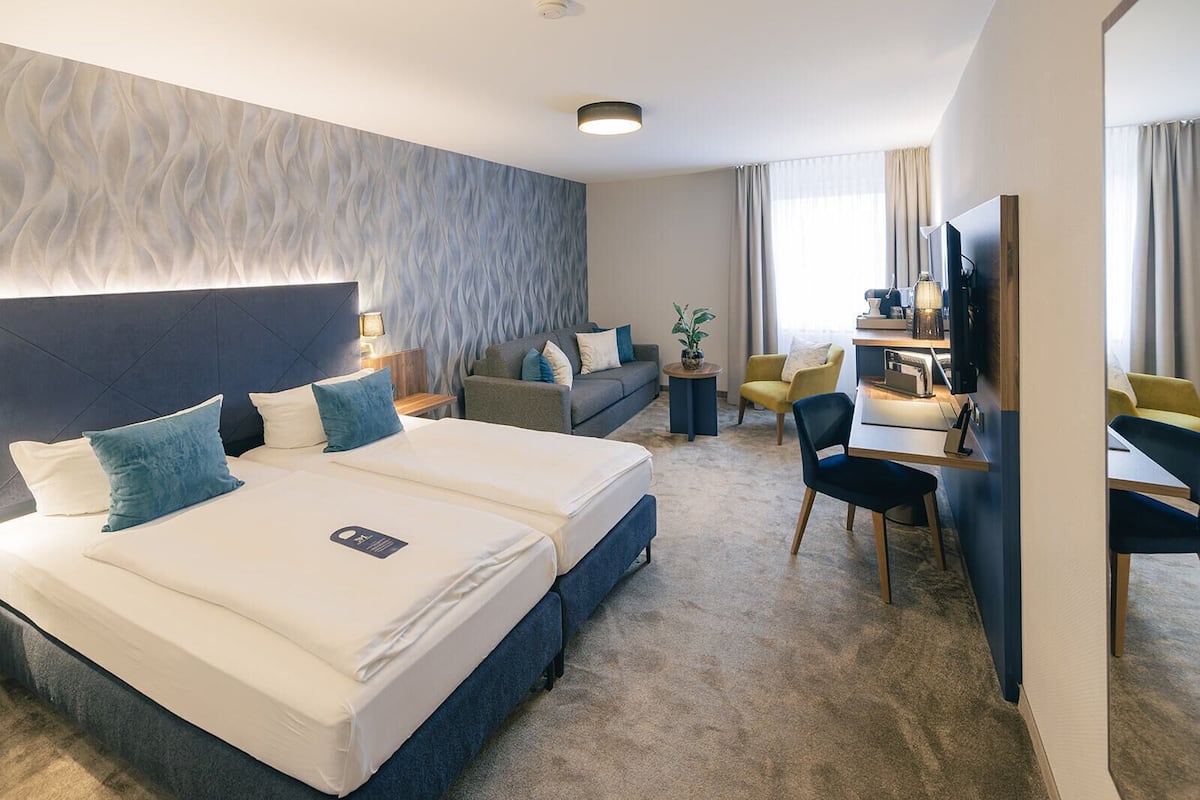 Ein Hotelzimmer mit einem großen Bett, einem Schreibtisch, einer Couch und einem Fernseher.