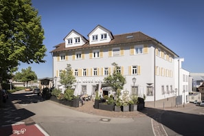 Ein Hotel mit weißer Fassade, gelben Fensterrahmen und einer roten Fahrradspur.